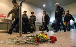 Passengers walk past flowers left on a floor in memory of those killed in Monday's blast at Moscow's Domodedovo airport